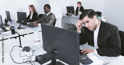 Schilderij op canvas Upset Hispanic businessman worriedly looking at computer monitor