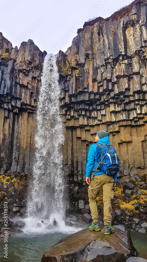 Iceland - A man standing in front of a Svartifoss waterfall