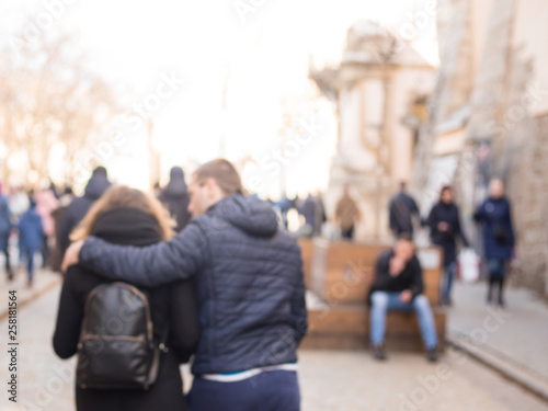 Man and a woman with backpack walking down the street hugging. The photo is made out of focus, no faces are recognisable