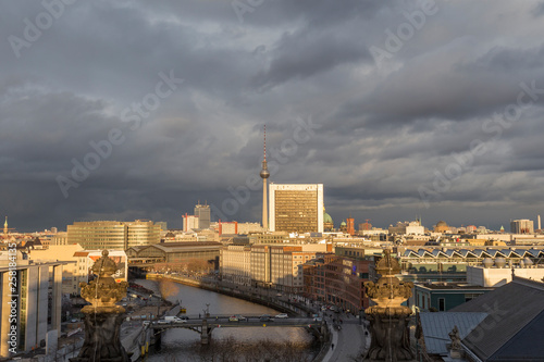 View of the Spree River, Fernsehturm TV Tower and buildings at the downtown Berlin, Germany, on a sunny day. Dark clouds. Copy space.