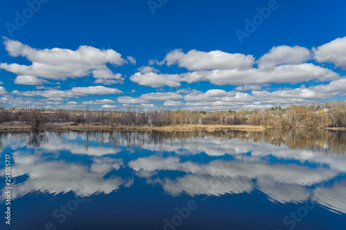 Fototapeta Naklejka Na Ścianę i Meble -  Trees with spring sky and clouds in the reflection of water.