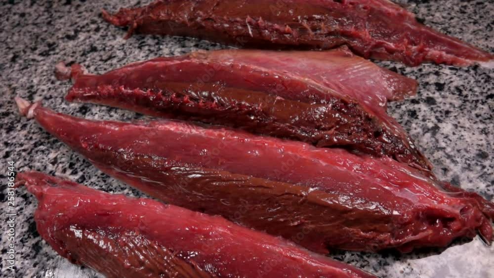 Tuna cut into pieces lies on a gray marble table. Tuna cut into pieces lies on a gray marble table.