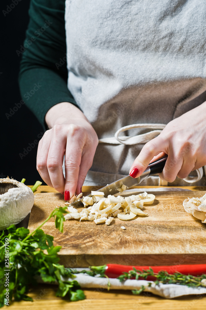 The chef cut the mushroom. Black background, side view, kitchen, space for text