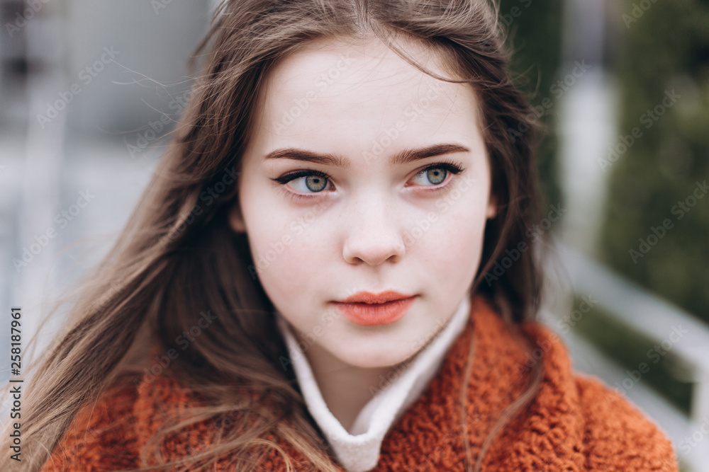 Obraz premium Outdoor urban portrait of cheerful beautiful caucasin young girl in coat. Casual style concept