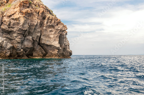 detail of coast of the island of Ischia with cloudy sky and wavy sea