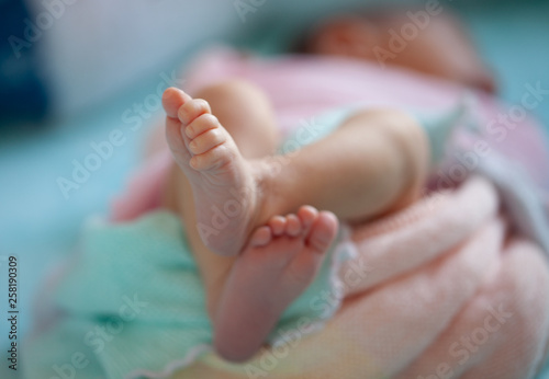 Newborn baby feet close up. Soft pastels background, Aquamarine, pink, peach wrap.