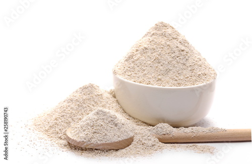 Integral barley flour pile with wooden spoon and porcelain bowl isolated on white background, clipping path