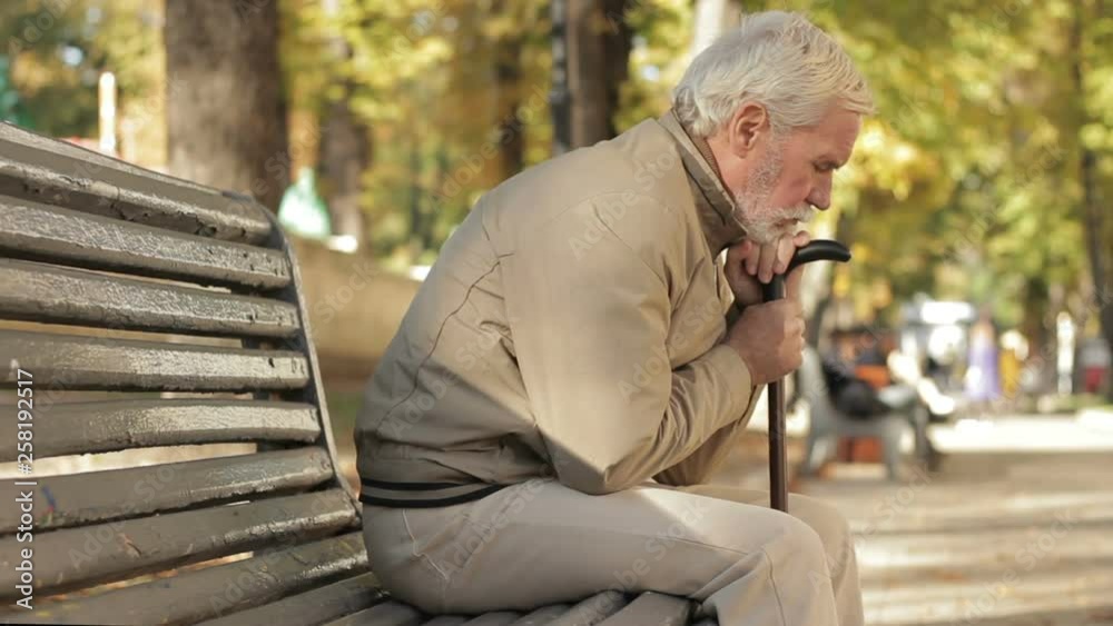 Thoughtful older adult in bad mood sitting in park. Fall age depression disease