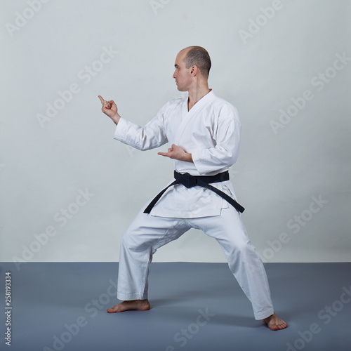 On a gray cover man in karategi performs formal karate exercises