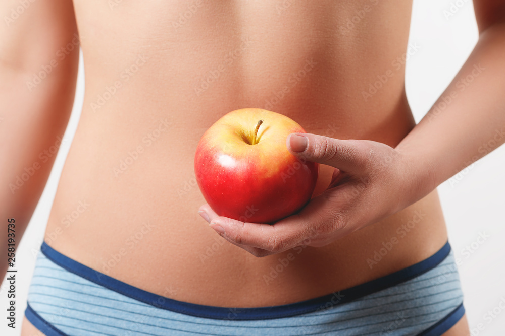 close up. slender slim figure waist belly young woman girl. Holding a juicy red Apple. isolated on white background close up. slender slim figure waist belly young woman girl. Holding a juicy red Apple. isolated on white background