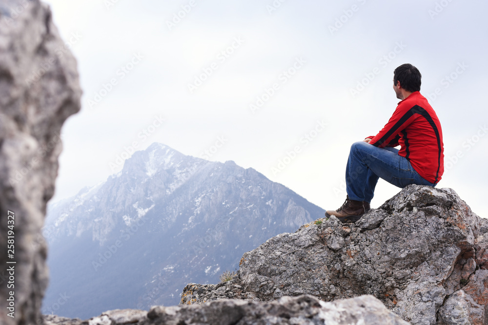 Young Man enjoy on top of the mountain. Concept of freedom, man on cliff high in mountains
