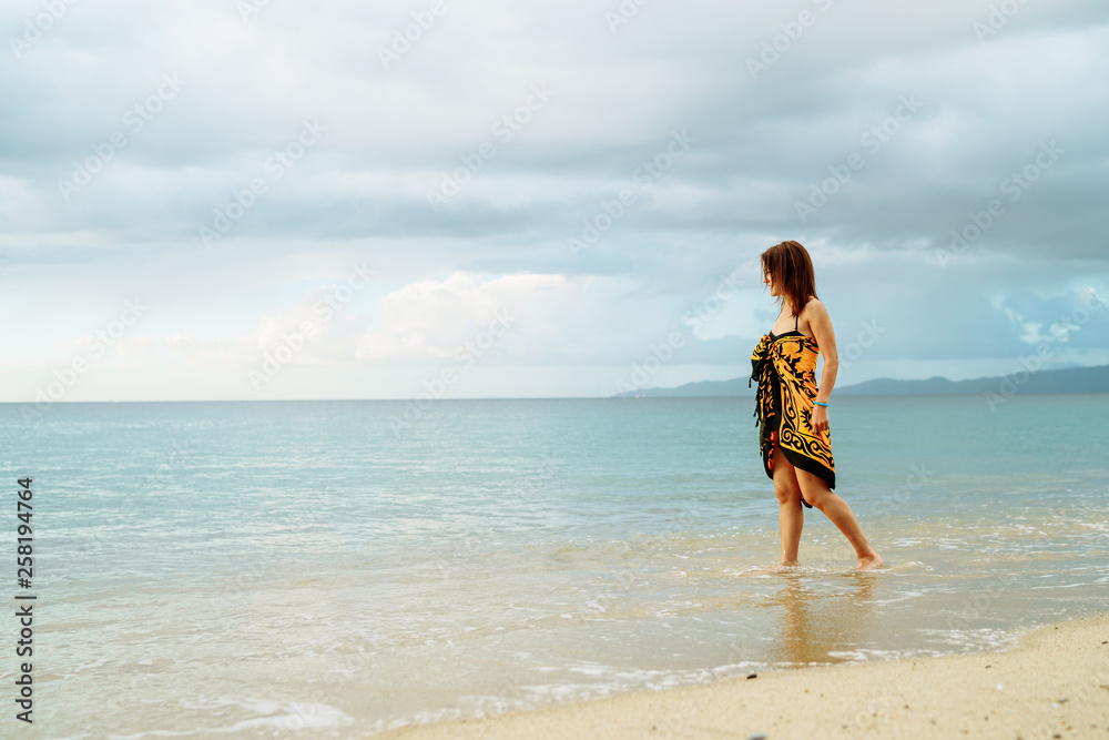 beautiful young girl in pareo walking on the sunset beach on sunlight in Philippines - Summer vacation background