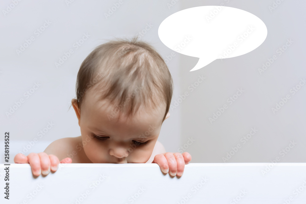 Baby girl thinking about something while standing in her crib. Baby girl thinking about something while standing in her crib.