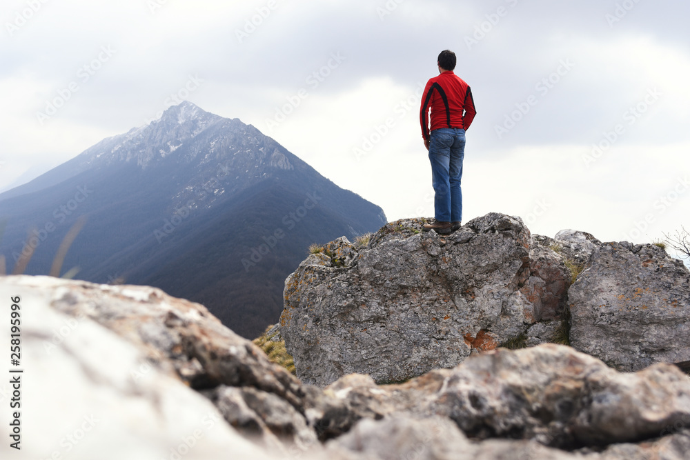 Young Man enjoy on top of the mountain. Concept of freedom, man on cliff high in mountains