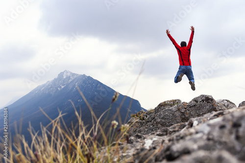 Man jump and rise hands on top of the mountain. Concept of freedom, man on wild nature in mountains