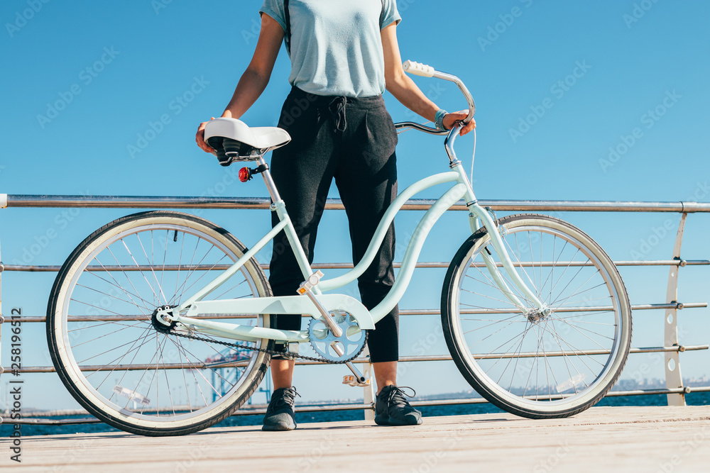 Unrecognizable young woman standing after bike