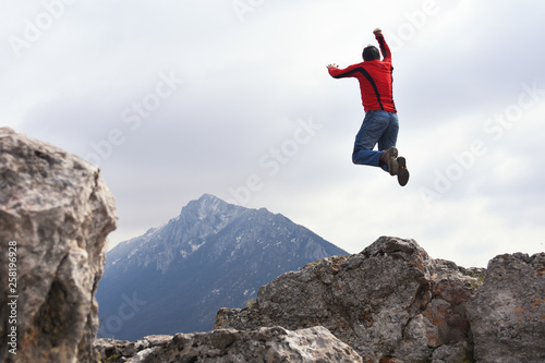 Man jump and rise hands on top of the mountain. Concept of freedom, man on wild nature in mountains