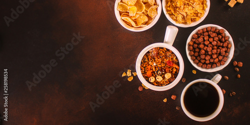 cornflakes, coffee, cottage cheese, bread, butter, eggs, jam and other ingredients for breakfast on a dark background. Top view with copy space