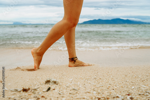 Woman walking on the beach leaving footprints in the sand