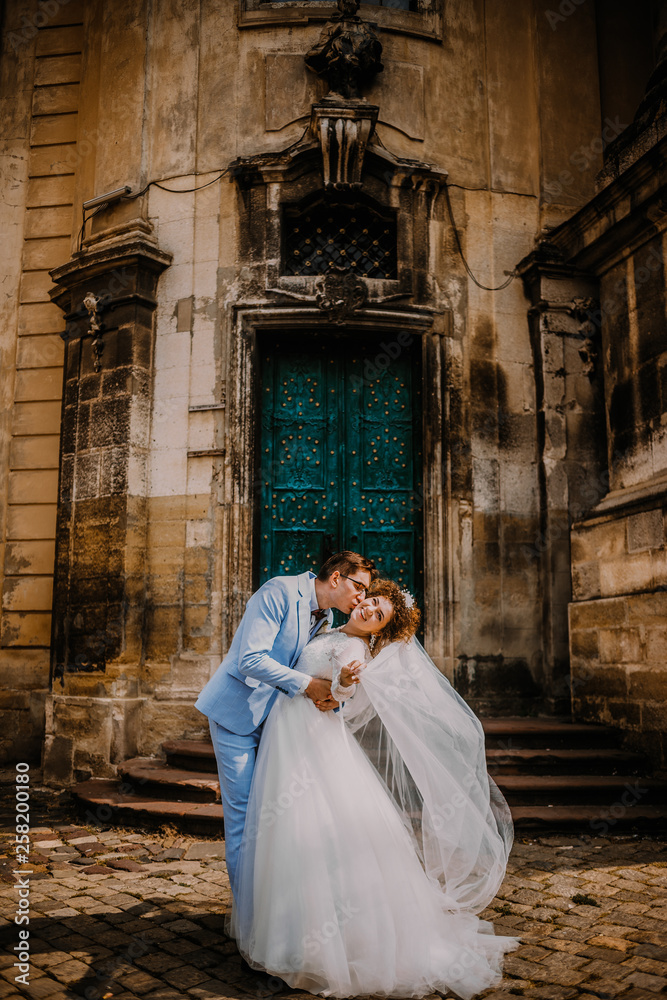 Young beautiful couple bride and groom kisses each others on the background of the church