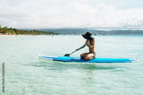 Woman is enjoying a view in standup paddleboarding over the ocean