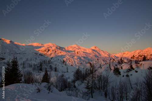 Sunset in snowcaped mountains. Mountains are orange color. Slovenia, Juliana Alps, Komna. The paradise for ski touring and snowshoeing photo