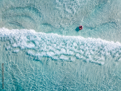 Aerial shot of swimmers on a beautiful beach with blue water and white sand