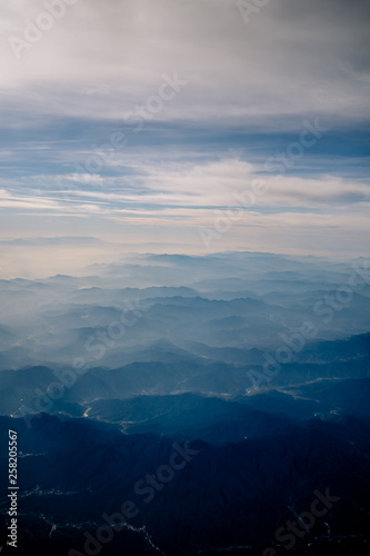 An aerial view of Chinese mountains from the airplane flying high above the ground. A look from the plane window.