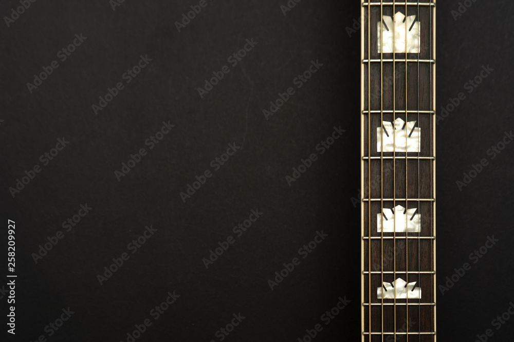Acoustic guitar neck on the right on black background. Space for text