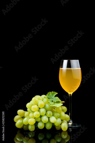 Glass of wine and grape on black background