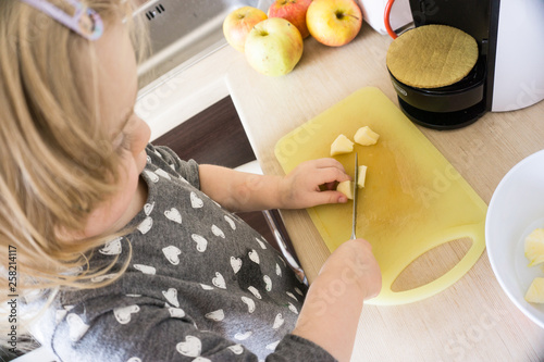 Little girl cutting apples for preparion smoothie