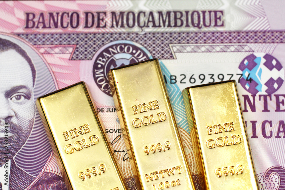 A close up image of a twenty metical bank note from Mozambique with three small golden ingots in macro