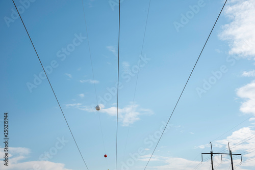 Electric poles with wires and cables set on a bright blue daylight sky.