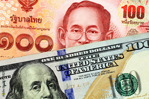 A close up imgae of a red one hundred Thai baht with an American one hundred dollar bill in macro photo