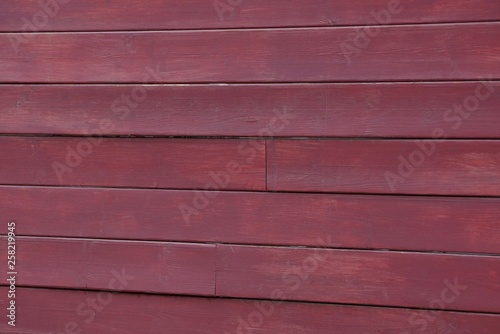 red wooden background of thin boards in the wall of the fence