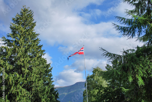 Norwegian Flag in Sogndal Norway between two trees, fluttering in the breeze or wind. 