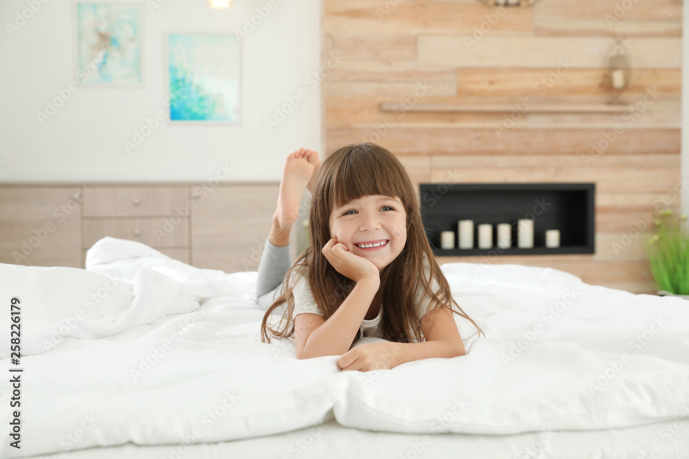 Cute little girl lying on bed at home