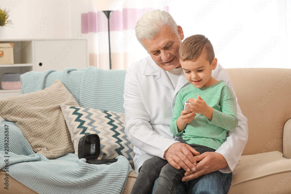 Doctor and little patient with digital glucose meter at home. Diabetes control Doctor and little patient with digital glucose meter at home. Diabetes control