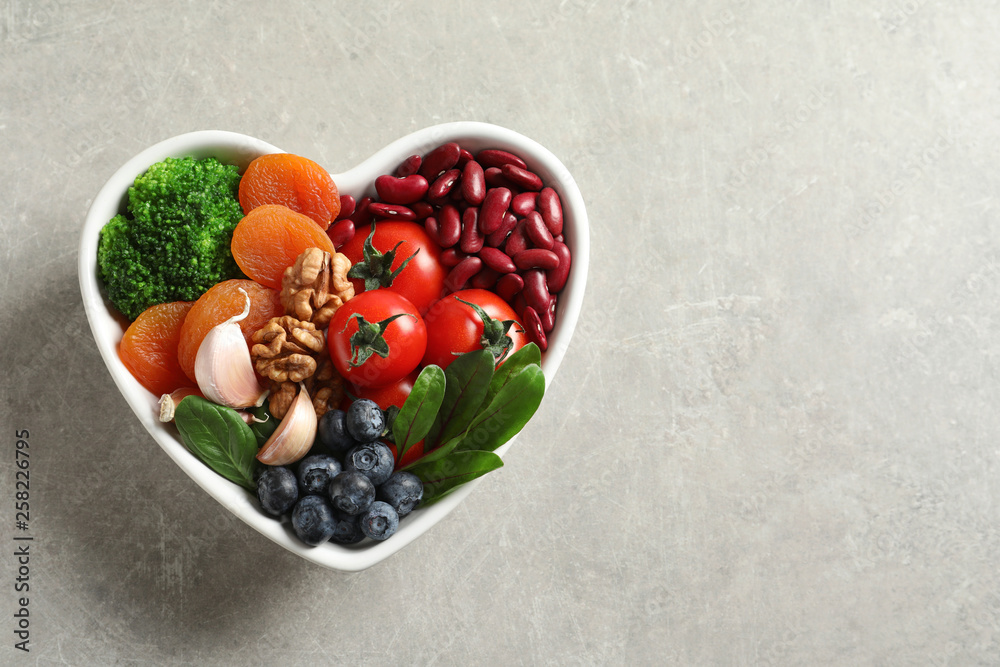 Bowl with heart-healthy diet products on grey background, top view. Space for text Bowl with heart-healthy diet products on grey background, top view. Space for text