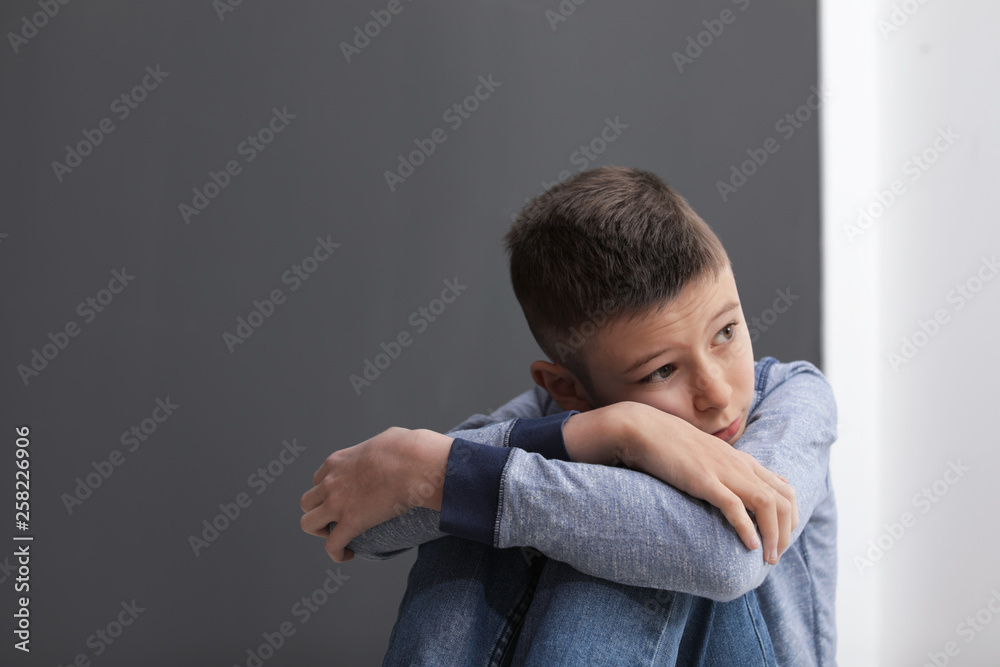 Upset preteen boy sitting indoors. Space for text Upset preteen boy sitting indoors. Space for text