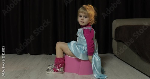 Little girl sitting on the potty and watching TV