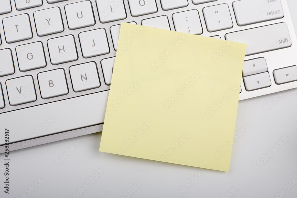 Yellow memo on white keyboard Yellow memo on white keyboard