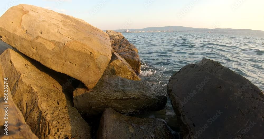 Seaside view of beach rocks with the sea and a industrial port behind it. Seaside view of beach rocks with the sea and a industrial port behind it.