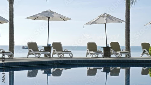 Reflections on Pool of Luxury Hotel With Beds Umbrellas and View on Ocean Horizon on Sunny Summer Afternoon photo