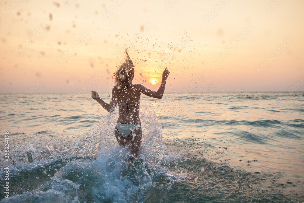 Woman running into the sea with lots of splashes