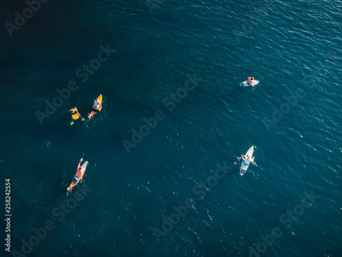 Surfers with surfboards in blue ocean waiting wave. Aerial view with drone