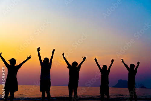 A group of women rise hands up to sky freedom concept with blue sky and beach sunset.