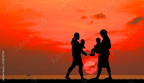 silhouette happy family on the beach at sunrise time