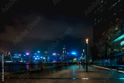 Hong Kong cityscape at night. Tourists walking on the waterfront