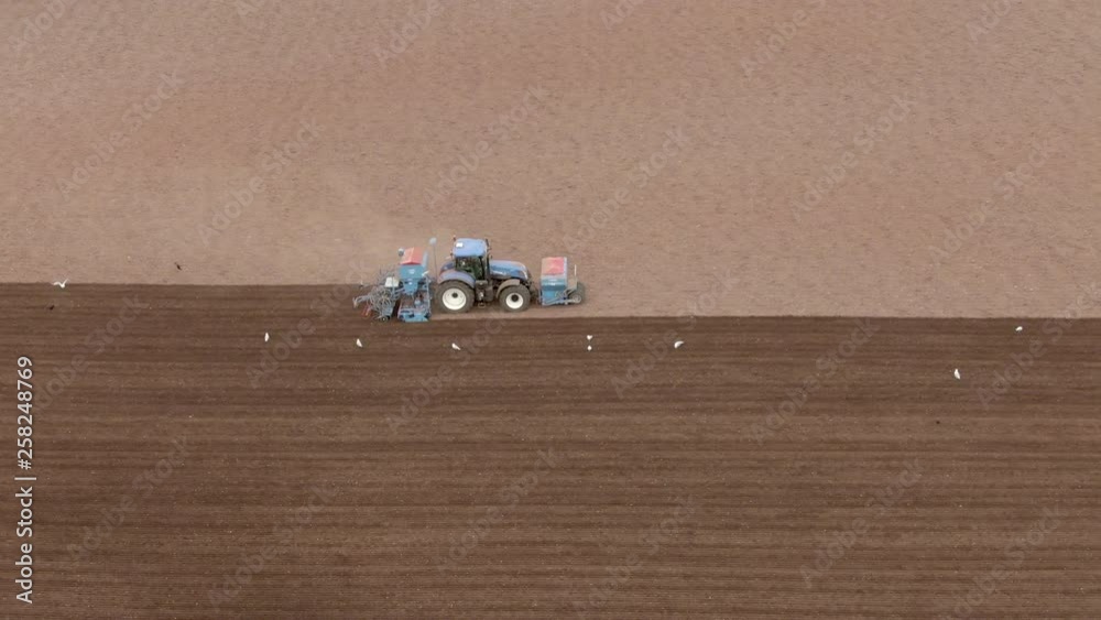 Aerial side tracking shot of the right hand side of a tractor as it ploughs a field, Aberdeenshire, Scotland